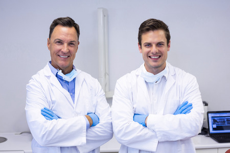 Portrait of happy dentists standing with arms crossed in clinicの写真素材