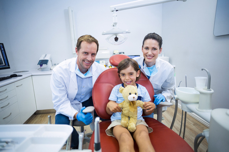 Portrait of smiling dentists and young patient in dental clinicの写真素材