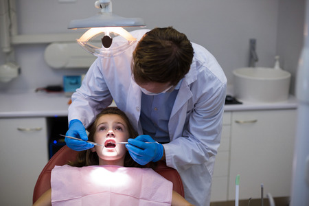 Dentist examining a young patient with tools in dental clinicの写真素材