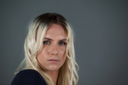 Portrait of transgender woman with blond hair gray backgroundの写真素材