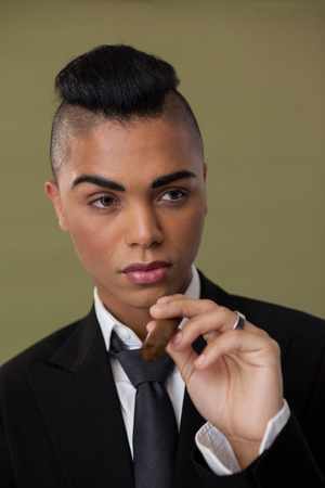 Close up of transgender woman holding cigarette on green backgroundの写真素材