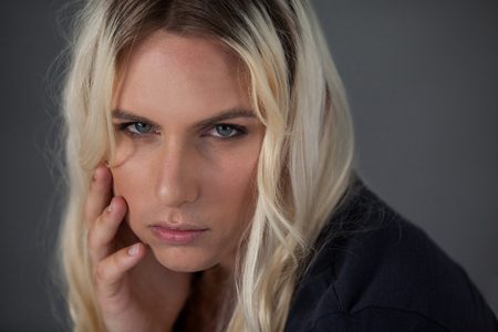 Close up portrait of beautiful transgender woman against gray backgroundの写真素材