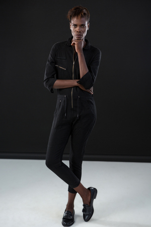 Androgynous man posing with hand on his chin against grey backgroundの写真素材