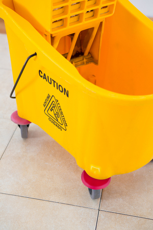 Close up of yellow mop bucket on tiled floorの写真素材