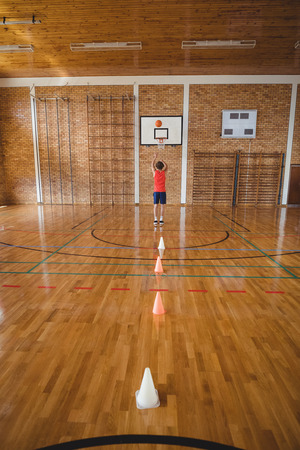 Determined high school boy playing basketball in the courtの写真素材