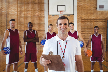Portrait of smiling coach and basketball player standing in the courtの写真素材