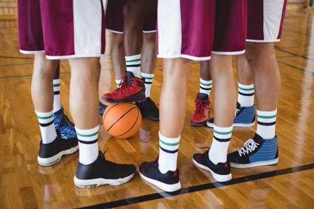 Low section of basketball players forming a huddle in the courtの写真素材