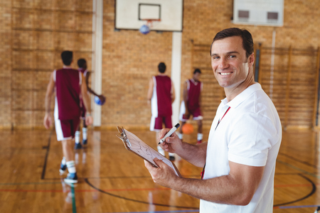 Portrait of basketball coach holding clipboard in the courtの写真素材