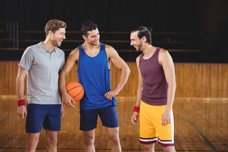 Happy male basketball players laughing in basketball courtの写真素材