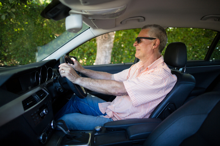 Senior man wearing sunglasses while driving carの写真素材