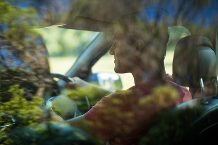 Rear view of man seen through car windshieldの写真素材
