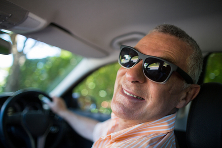 Portrait of smiling senior man wearing sunglasses while traveling in carの写真素材