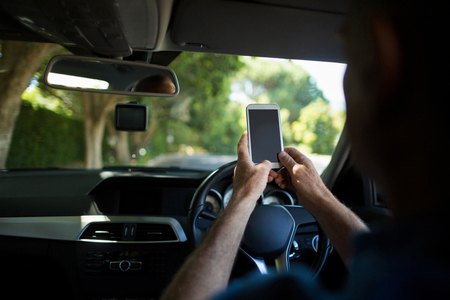 Cropped image of man using mobile phone in carの写真素材
