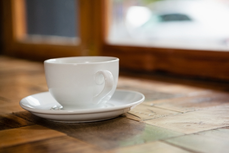 Close up of cup and saucer on wooden table at cafe shop