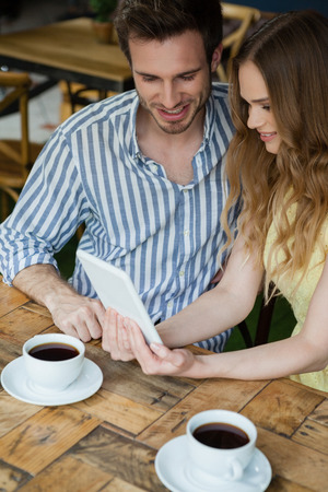 High angle view of couple using tablet computer while sitting at coffee shopの写真素材