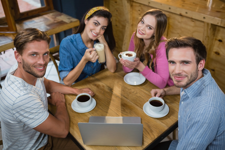 Portrait of happy friends having coffee at table in cafÃ©の写真素材