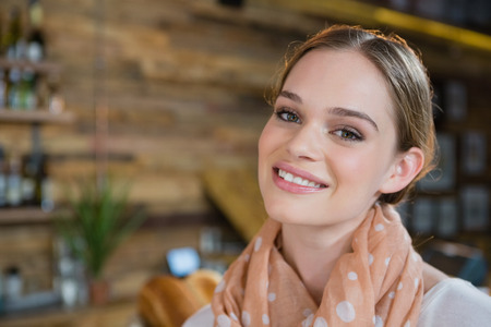 Portrait of smiling woman standing near counter in cafeの写真素材