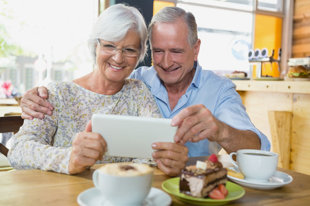 Happy senior couple using digital tablet in cafÃ©の写真素材