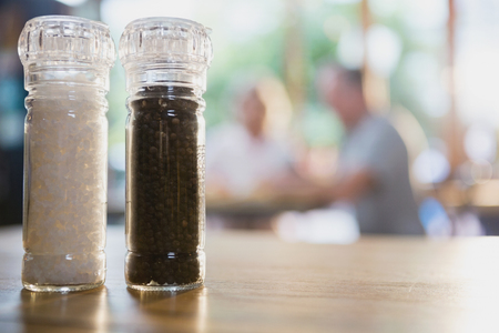 Salt and black pepper shakers on a table in cafÃ©の写真素材