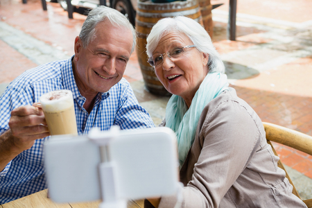 Senior couple taking selfie from mobile phone in outdoor cafÃ©の写真素材