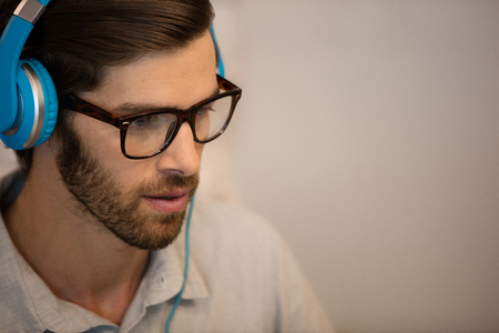 Young businessman wearing blue headphones in officeの写真素材