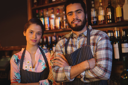 Portrait of waiter and waitress standing with arms crossed in pubの写真素材