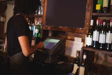 Young waiter using a machine in pubの写真素材