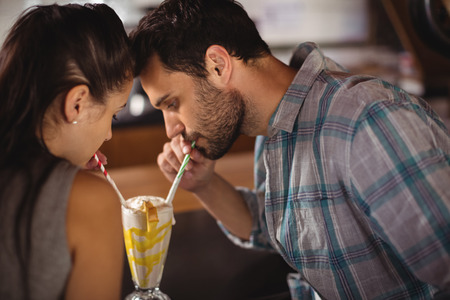 Close-up of couple having milkshake in restaurantの写真素材