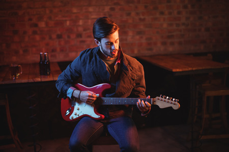 Young man playing guitar in pubの写真素材