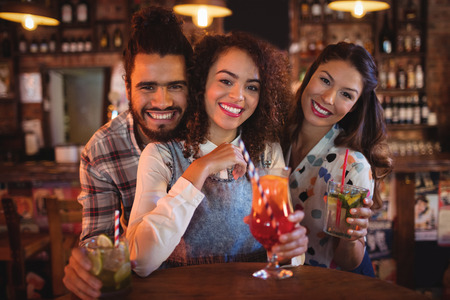 Portrait of young friends having drinks in pub