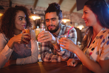 Young friends interacting with each other having drinks in pubの写真素材
