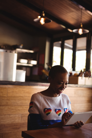 Happy woman using digital tablet in restaurantの写真素材