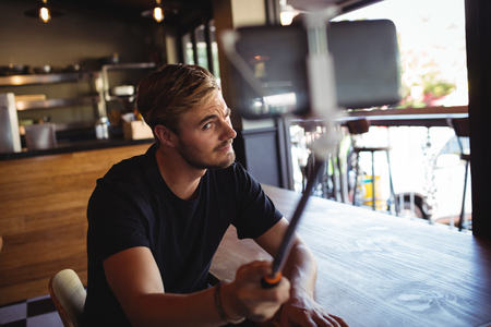Man taking selfie from mobile phone in restaurantの写真素材