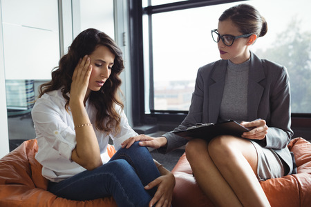 Counselor consoling unhappy woman during therapyの写真素材