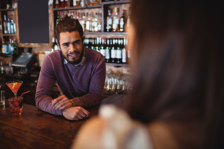 Male bar tender interacting with customer at pubの写真素材