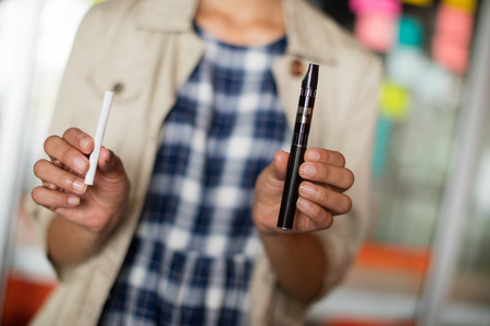 Mid-section of female executive holding electronic cigarette in officeの写真素材