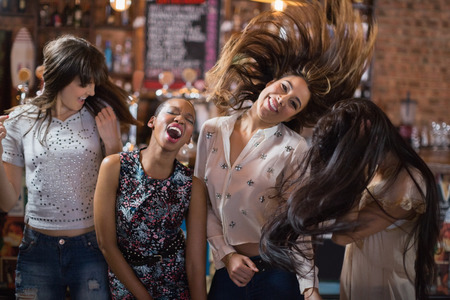 Cheerful female friends dancing at pubの写真素材