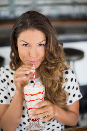 Portrait of woman having drink in restaurantの写真素材