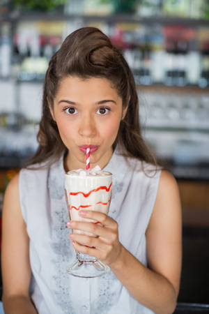 Portrait of young woman drinking smoothie at restaurantの写真素材