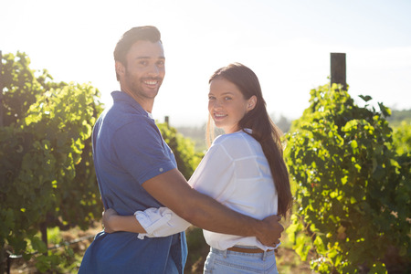 Portrait of smiling couple embracing at vineyard during sunny dayの写真素材