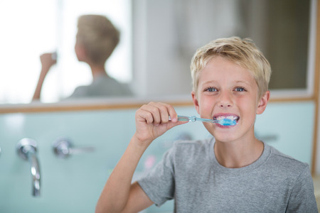 Portrait of boy brushing his teeth in bathroom at homeの写真素材