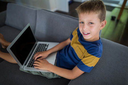 Portrait of boy using laptop in living room at homeの写真素材