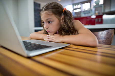 Cute girl looking at laptop in kitchenの写真素材