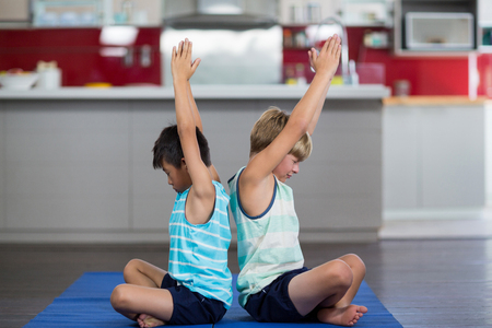 Siblings performing yoga at homeの写真素材