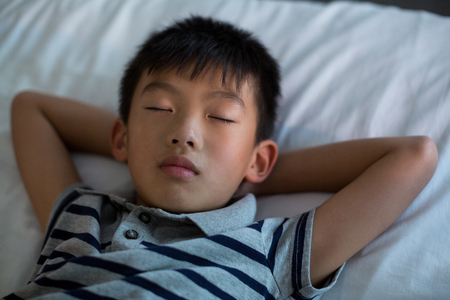Boy sleeping on bed in bedroom at homeの写真素材