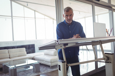 Portrait of mature interior designer standing by workbench in office
