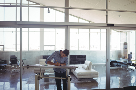 Focused male interior designer drawing on workbench in office