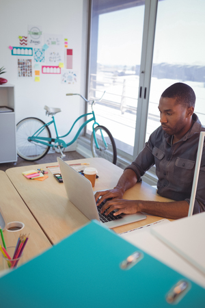Young businessman using laptop on desk in officeの写真素材