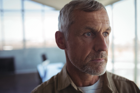 Close up of mature businessman looking away in officeの写真素材