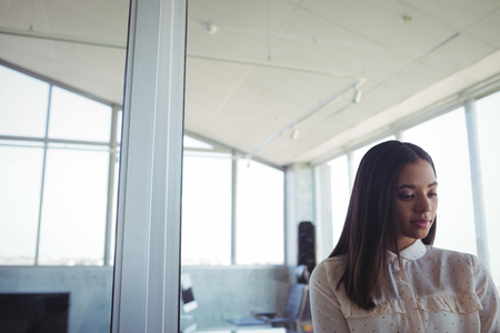 Close up of thoughtful businesswoman standing in officeの写真素材